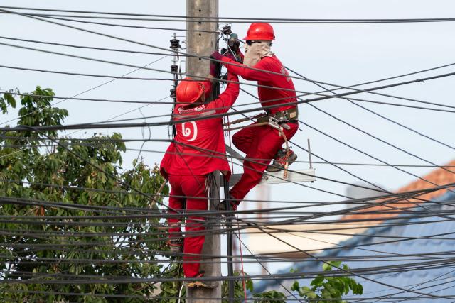 In this photo taken on August 22, 2026, electrical technicians carry out maintenance work in the Hadxayfong district of Vientiane. Isolated, under-developed Laos brands itself the "Battery of Southeast Asia", powering its neighbours with dozens of hydroelectric plants, but frequent power outages leave its own people in the dark. (Photo by AFP) / TO GO WITH: Laos-energy-electricity, by Beatrice SIVIERO