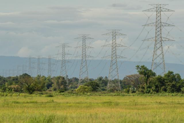 This photo taken on August 22, 2026, shows a series of high-voltage transmission lines that cross the Mekong River in Hadxayfong district, Vientiane, as part of the network through which the country exports electricity to neighbouring Thailand. Isolated, under-developed Laos brands itself the "Battery of Southeast Asia", powering its neighbours with dozens of hydroelectric plants, but frequent power outages leave its own people in the dark. (Photo by AFP) / TO GO WITH: Laos-energy-electricity, by Beatrice SIVIERO