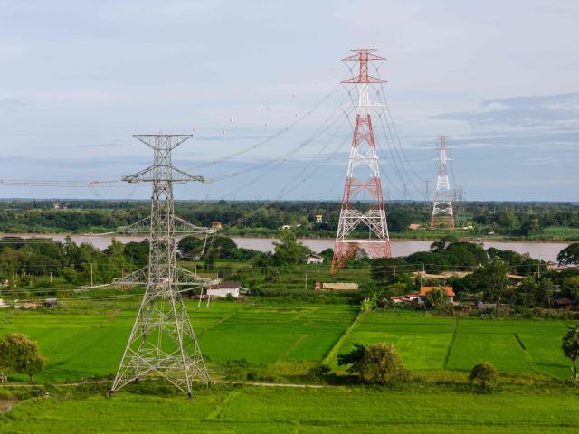 In this aerial photo taken on August 22, 2026, high-voltage transmission lines cross the Mekong River in Hadxayfong district, Vientiane, as part of the network through which the country exports electricity to neighbouring Thailand. Isolated, under-developed Laos brands itself the "Battery of Southeast Asia", powering its neighbours with dozens of hydroelectric plants, but frequent power outages leave its own people in the dark. (Photo by AFP) / TO GO WITH: Laos-energy-electricity, by Beatrice SIVIERO