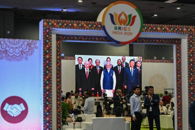 Mediapersons watch a digital screen showing leaders of participating countries gather for a family photograph during the 18th BRICS Summit in New Delhi on September 13, 2026. (Photo by Arun SANKAR / AFP)
