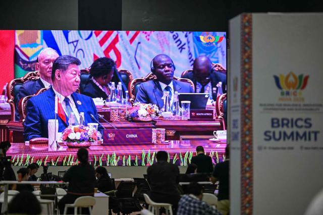 Mediapersons watch a digital screen showing China's President Xi Jinping (L) attending the 18th BRICS Summit at the Bharat Mandapam in New Delhi on September 13, 2026. (Photo by Arun SANKAR / AFP)