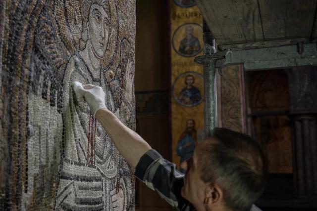 Leonid Kolodnytsky, restoration artist of the Scientific Restoration Workshop of the National Reserve "Sophia of Kyiv", cleans mosaic during scheduled restoration works in the St. Sophia Cathedral in Kyiv on September 11, 2026, amid the Russian invasion of Ukraine. Despite the constant threat of missile and drone attacks, restorers have uncovered three compositions hidden from view for more than 70 years at Saint Sophia Cathedral, an architectural monument of Kyivan Rus. The former cathedral is one of the city's best known landmarks and the first heritage site in Ukraine to be inscribed on the World Heritage List. (Photo by Genya SAVILOV / AFP)