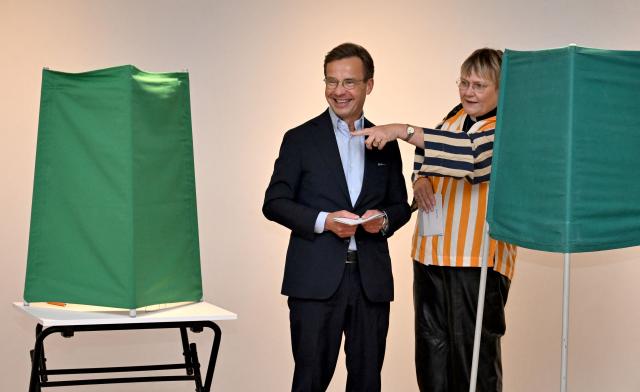 Sweden's Prime Minister Ulf Kristersson, leader of the conservative Moderates, stands next to his wife Birgitta Ed as he prepares to cast his ballot at a polling station in Strangnas near Stockholm, during Sweden's general election on September 13, 2026. Polling stations opened on September 13, 2026 in Sweden in what is expected to be a close general election that will see either the far right enter government for the first time or the left-wing opposition reclaim power. (Photo by Jonathan Nackstrand / AFP)