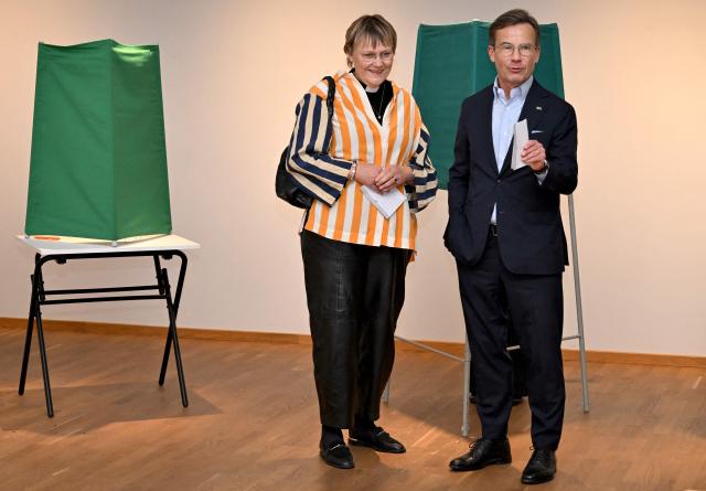Sweden's Prime Minister Ulf Kristersson, leader of the conservative Moderates, stands next to his wife Birgitta Ed as they prepare to cast their ballots at a polling station in Strangnas near Stockholm, during Sweden's general election on September 13, 2026. Polling stations opened on September 13, 2026 in Sweden in what is expected to be a close general election that will see either the far right enter government for the first time or the left-wing opposition reclaim power. (Photo by Jonathan Nackstrand / AFP)