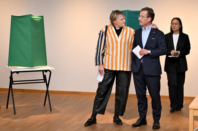 Sweden's Prime Minister Ulf Kristersson (C), leader of the conservative Moderates, stands next to his wife Birgitta Ed (L) and one of their adopted daughters as they prepare to cast their ballots at a polling station in Strangnas near Stockholm, during Sweden's general election on September 13, 2026. Polling stations opened on September 13, 2026 in Sweden in what is expected to be a close general election that will see either the far right enter government for the first time or the left-wing opposition reclaim power. (Photo by Jonathan Nackstrand / AFP)