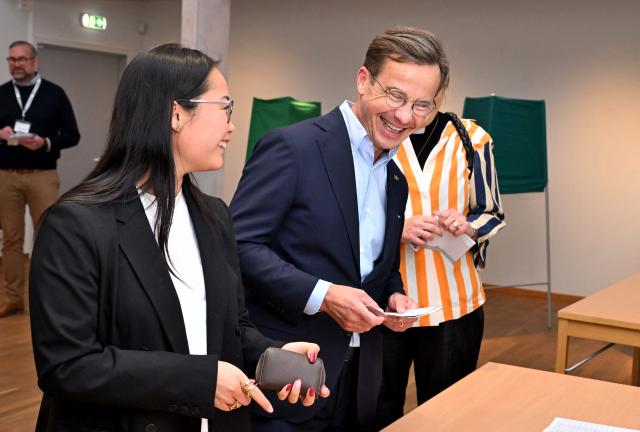 Sweden's Prime Minister Ulf Kristersson (C), leader of the conservative Moderates, stands next to his wife Birgitta Ed (R, hidden) and one of their adopted daughters (L) as they get their ballot papers and prepare to cast their ballots at a polling station in Strangnas near Stockholm, during Sweden's general election on September 13, 2026. Polling stations opened on September 13, 2026 in Sweden in what is expected to be a close general election that will see either the far right enter government for the first time or the left-wing opposition reclaim power. (Photo by Jonathan Nackstrand / AFP)