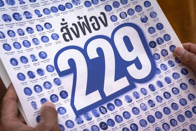Protesters hold sheets of paper bearing the faces of people allegedly involved in collusion in the 2024 Senate election in Bangkok on September 13, 2026, a day before an Election Commission decision on whether to pursue collusion charges in the case. (Photo by Chanakarn LAOSARAKHAM / AFP)