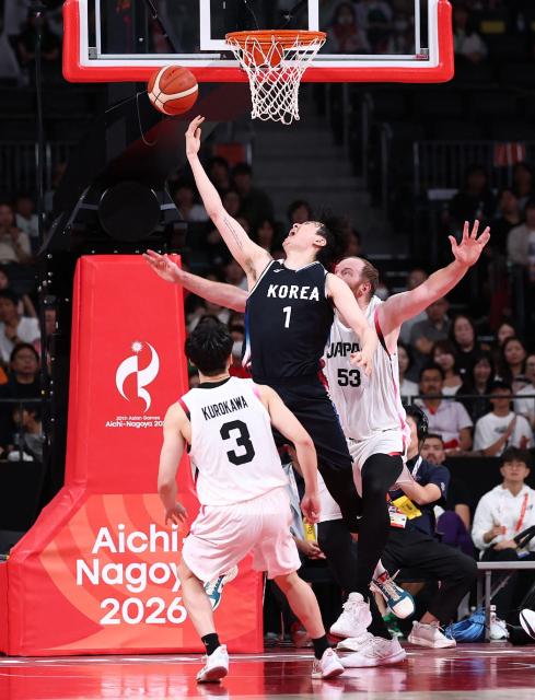South Korea's Lee Hyun-jung (C) is challenged by Japan's Alex Kirk (back) during their 2026 Asian Games men's group A basketball game at Aichi International Arena in Nagoya on September 13, 2026. (Photo by JIJI Press / AFP) / Japan OUT