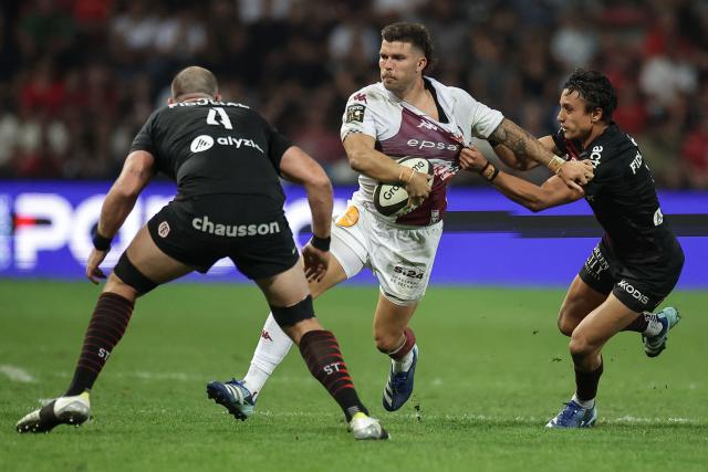 Bordeaux-Bègles' French fly-half Matthieu Jalibert (C) is tackled by Toulouse's French wing Ange Capuozzo (R) during the French Top 14 rugby union match between Stade Toulousain and Bordeaux-Begles at the Stade Ernest-Wallon in Toulouse, southwestern France on September 13, 2026.  (Photo by Valentine CHAPUIS / AFP)