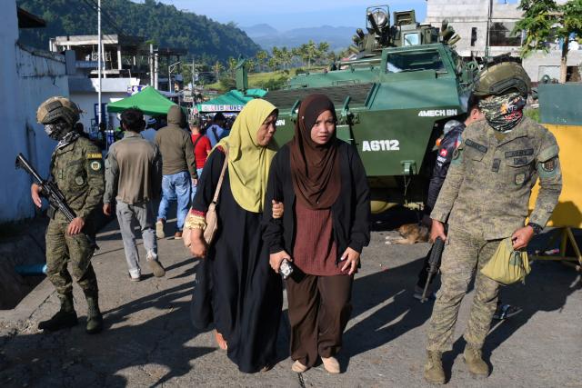 Soldiers keep watch as voters head to a polling station in Marawi City on the southern island of Mindanao on September 14, 2026, for the first elected parliament in the Bangsamoro Autonomous Region in Muslim Mindanao (BARMM) in the Philippines' far south. Voters across the Philippines' autonomous Muslim region began casting ballots for their first elected parliament on September 14, hours after gun violence left at least three people dead outside a polling station. (Photo by Ted ALJIBE / AFP)