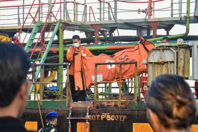 Rescue personnel carry a body bag containing clothes of victims of the Virgo Transport 8 passenger ferry, which capsized September 13 carrying 213 passengers and 30 crew while en route from Banjarmasin to Surabaya, at the port in Banjarmasin, South Kalimantan, on September 14, 2026. Indonesian rescuers searched on September 14 for more than 100 people missing after a ferry capsized in rough seas, with aircraft, naval vessels and divers deployed to find survivors, the country's top rescue official said. (Photo by MUDA SAGALA / AFP)