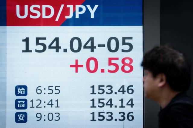 A man walks past an electronic quotation board displaying the foreign exchange rate of the Japanese yen against the US dollar in Tokyo on September 14, 2026. (Photo by Yuichi YAMAZAKI / AFP)