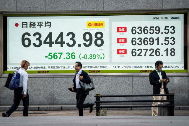 People walk past an electronic quotation board displaying the Nikkei Stock Average on the Tokyo Stock Exchange in Tokyo on September 14, 2026. (Photo by Yuichi YAMAZAKI / AFP)
