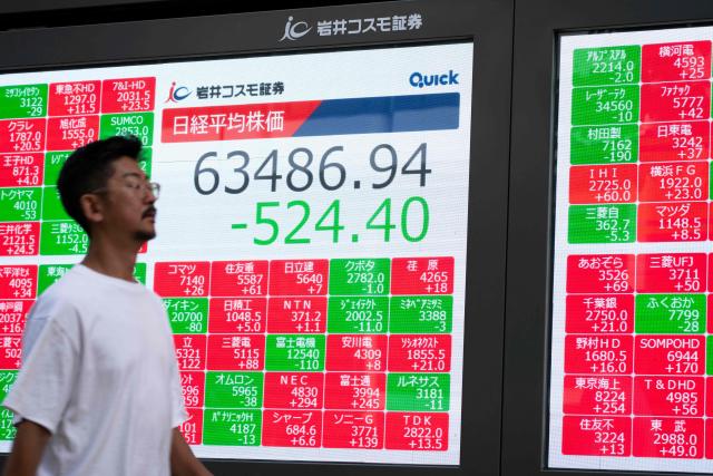A man walks past an electronic quotation board displaying the Nikkei Stock Average on the Tokyo Stock Exchange in Tokyo on September 14, 2026. (Photo by Yuichi YAMAZAKI / AFP)