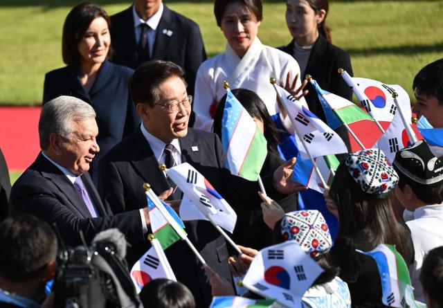 Uzbekistan's President Shavkat Mirziyoyev (L) and South Korea's President Lee Jae Myung (2nd L) attend a welcoming ceremony at the presidential Blue House in Seoul on September 14, 2026, on the sidelines of the 1st Korea-Central Asia Summit. (Photo by JUNG YEON-JE / POOL / AFP)