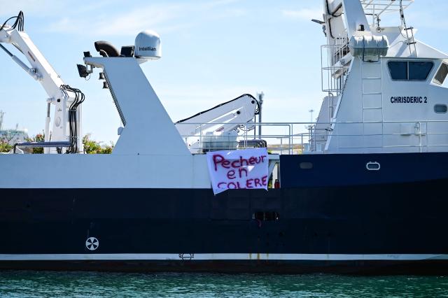 A banner reading "fisherman angry" hangs on anchored fishing boat at the entrance to the port in Sete, Southern France, on September 14, 2026. Mediterranean fishermen began a joint protest movement on September 14, 2026 over surging fuel costs and worsening working conditions, with a demonstration held outside the maritime affairs office in Sete and fishing boats blocking the port of Port-Vendres. (Photo by Gabriel BOUYS / AFP)