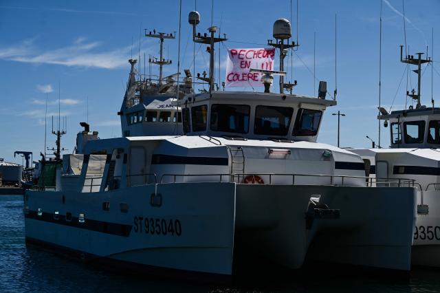 A banner reading "fisherman angry" hangs on anchored fishing boat at the entrance to the port in Sete, Southern France, on September 14, 2026. Mediterranean fishermen began a joint protest movement on September 14, 2026 over surging fuel costs and worsening working conditions, with a demonstration held outside the maritime affairs office in Sete and fishing boats blocking the port of Port-Vendres. (Photo by Gabriel BOUYS / AFP)