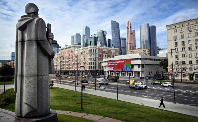 A woman walks past a monument to a Soviet World War Two (WWII) soldier and buildings of the Moscow International Business Centre (Moskva City) in western Moscow on September 14, 2026. (Photo by Alexander NEMENOV / AFP)