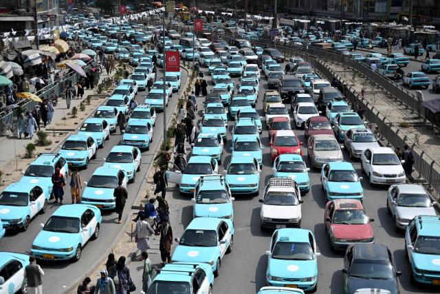 Commuters riding blue taxis wait in a traffic jam in Kabul on September 14, 2026. (Photo by Wakil KOHSAR / AFP)