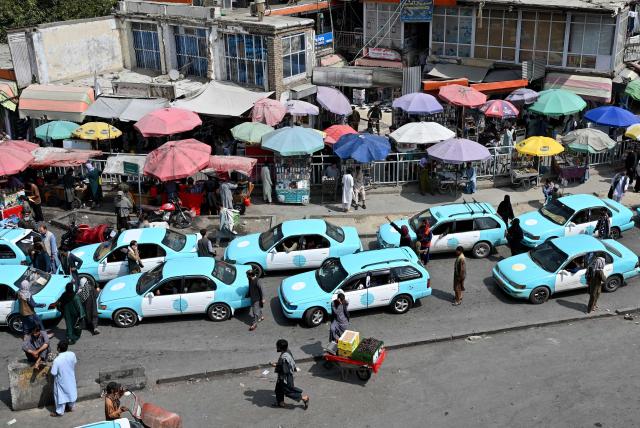 Commuters riding blue taxis wait in a traffic jam in Kabul on September 14, 2026. (Photo by Wakil KOHSAR / AFP)