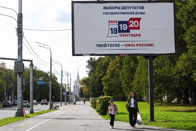 People walk past a billboard announcing the upcoming State Duma, Russia's lower house of parliament, election with the Moscow State University building in the background in Moscow on September 14, 2026. The 2026 parliamentary election will be held over a three-day period from September 18 to 20. (Photo by Igor IVANKO / AFP)