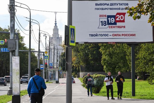 People walk past a billboard announcing the upcoming State Duma, Russia's lower house of parliament, election with the Moscow State University building in the background in Moscow on September 14, 2026. The 2026 parliamentary election will be held over a three-day period from September 18 to 20. (Photo by Igor IVANKO / AFP)