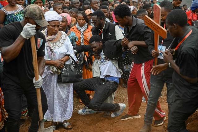 TOPSHOT - Grieving family members support a man who collapsed as they bid a final farewell to their children who died in the fire, while a young ,brother and sister  cries beside the body of her loved one during the collective burial at Ruzizi cemetery in Bukavu, on September 14, 2026. A fire and stampede at a school in the eastern Democratic Republic of Congo killed at least 26 children, the UN children's agency said on Friday, with some pupils leaping from windows on high floors to escape the carnage. (Photo by Jospin Mwisha / AFP)