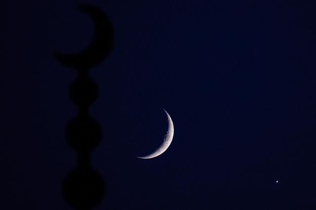 The waxing crescent moon and the planet Venus are pictured after sunset over Doha on September 14, 2026. (Photo by KARIM JAAFAR / AFP)