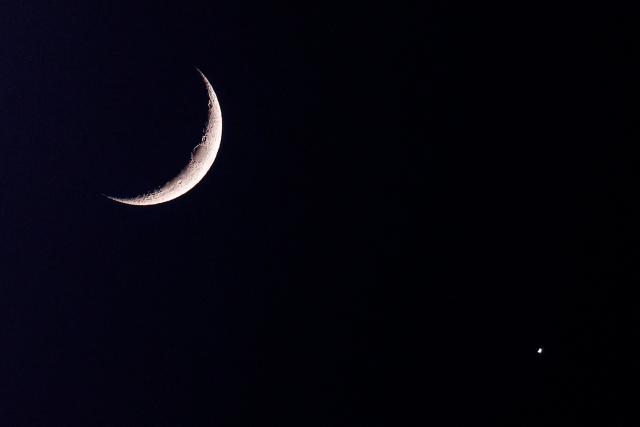 The waxing crescent moon and the planet Venus are pictured after sunset over Doha on September 14, 2026. (Photo by KARIM JAAFAR / AFP)