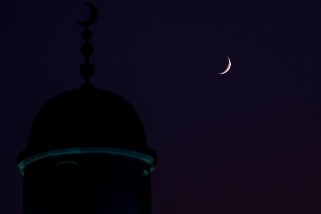 The waxing crescent moon and the planet Venus are pictured after sunset over Doha on September 14, 2026. (Photo by KARIM JAAFAR / AFP)