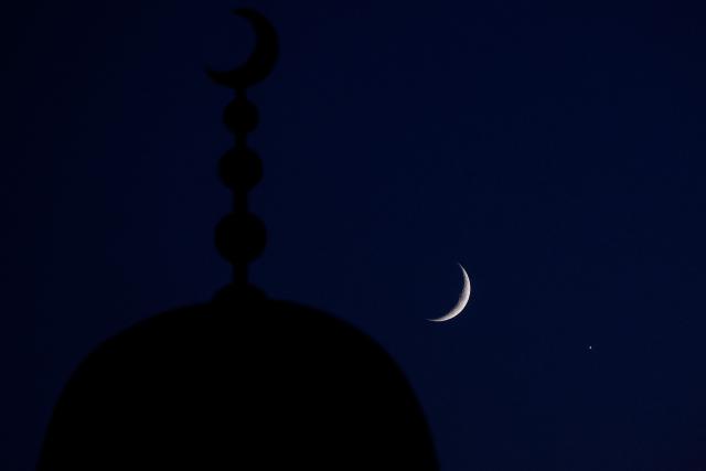 The waxing crescent moon and the planet Venus are pictured after sunset over Doha on September 14, 2026. (Photo by KARIM JAAFAR / AFP)