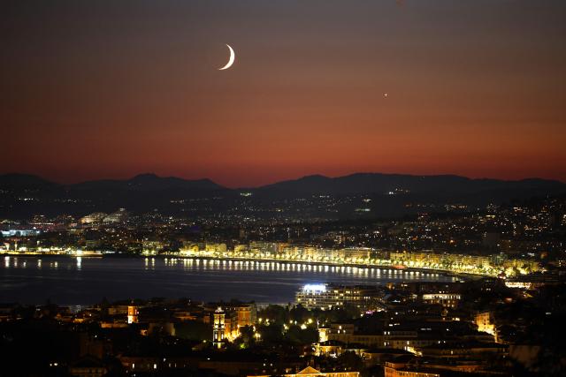 This photograph shows a waxing crescent moon and the planet Venus (R) at sunset over the "Baie des anges" on the French riviera city of Nice, on September 14, 2026. (Photo by Valery HACHE / AFP)