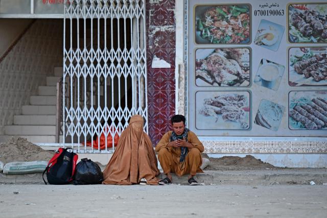 An Afghan man and a burqa-clad woman sit at a market in Spin Boldak district of Afghanistan's Kandahar province on September 15, 2026. (Photo by Sanaullah SEIAM / AFP)