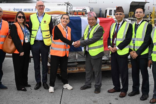 Nepal's Minister of Science, Mahabir Pun and French Ambassador to Nepal, Françoise Puig-Inza shake hands upon receiving relief supplies from the French government in the aftermath of flash floods, at the Tribhuvan International Airport in Kathmandu on September 15, 2026. (Photo by PRAKASH MATHEMA / AFP)