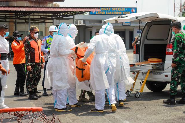 Rescue personnel carry a body bag containing a victim of the Virgo Transport 8 passenger ferry, which capsized on September 13 carrying 213 passengers and 30 crew while en route from Banjarmasin to Surabaya, at Syamsudin Noor International Airport in Banjarbaru, South Kalimantan on September 15, 2026. Indonesian rescuers searched on September 14 for more than 100 people missing after a ferry capsized in rough seas, with aircraft, naval vessels and divers deployed to find survivors, the country's top rescue official said. (Photo by INFUZ / AFP)