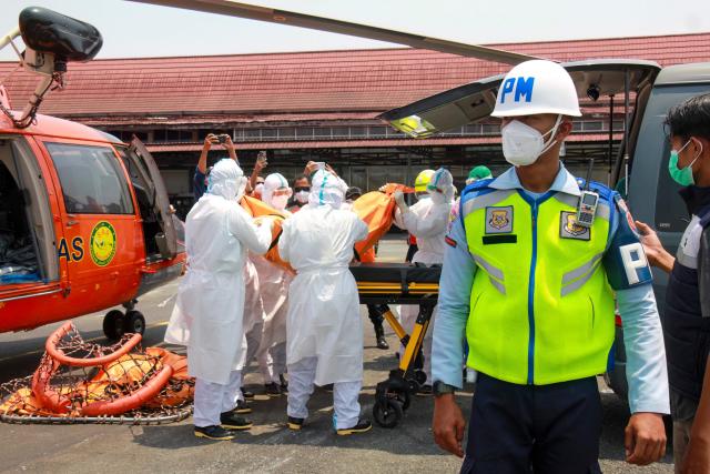 Rescue personnel carry a body bag containing a victim of the Virgo Transport 8 passenger ferry, which capsized on September 13 carrying 213 passengers and 30 crew while en route from Banjarmasin to Surabaya, at Syamsudin Noor International Airport in Banjarbaru, South Kalimantan on September 15, 2026. Indonesian rescuers searched on September 14 for more than 100 people missing after a ferry capsized in rough seas, with aircraft, naval vessels and divers deployed to find survivors, the country's top rescue official said. (Photo by INFUZ / AFP)