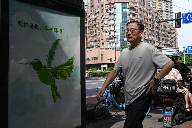 A man walks past a billboard on a street in Shanghai on September 15, 2026. (Photo by Jade GAO / AFP)
