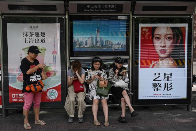 People wait for buses at a bus station on a street in Shanghai on September 15, 2026. (Photo by Jade GAO / AFP)