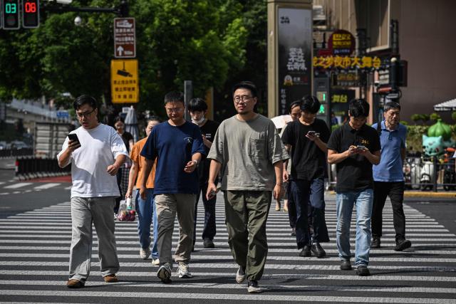People cross the pedestrian road on a street in Shanghai on September 15, 2026 (Photo by Jade GAO / AFP)