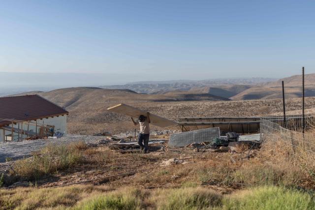 An Israeli settler carries material during the building of a structure on the outskirt of the illegal Israeli settlement at Malachei HaShalom in the Israeli-occupied Palestinian West Bank on September 15, 2026. Israeli rights group B'Tselem said September 14, 2026, that Israeli actions in the occupied West Bank form part of a greater project designed to make it impossible for Palestinians to exist together as a people. In a report titled "The Elimination Project", the group alleged five connected Israeli tactics and policies in the West Bank: "violence, ethnic cleansing, movement restrictions, economic strangulation, social and political destruction". Israeli settlements are illegal under international law. (Photo by Ilia YEFIMOVICH / AFP)