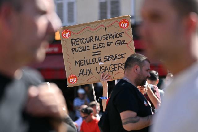 Protesters including one with a placard reading "back to public service for electricity and gas equals a better service for users" take part in a demonstration at the call of several workers' unions of the electricity and gas sector against a government plan to remove the "tarif agent", a preferential energy rate on electricity and gas consumption for employees and retirees of the electricity and gas industries, in Paris on September 15, 2026. Electricity and gas workers staged a massive strike on September 15, 2026, to protest plans to roll back their preferential energy rates, a benefit that is part of their compensation package, with some 59% of EDF SA employees (excluding subsidiaries) participating by midday, according to management. This level of participation, calculated on the company’s total workforce, is “historic,” according to the CFE-CGC, the company’s leading union, which notes that it already exceeds the participation rate recorded at the end of the day during the previous action to defend the employee tariff in 2011. (Photo by LOU BENOIST / AFP)