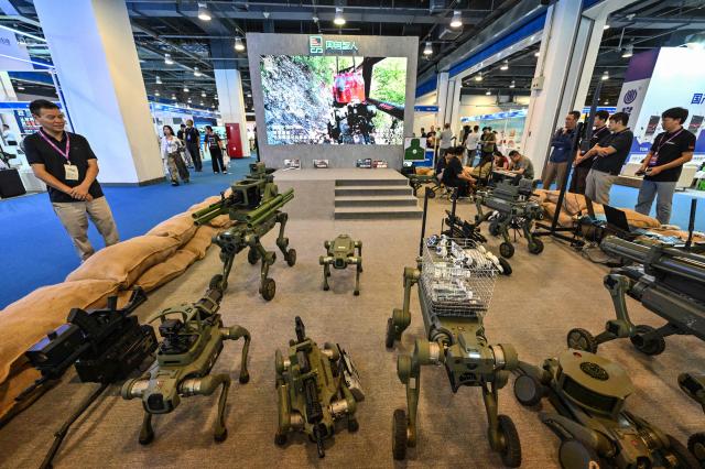 People look at robot dogs made for military and police usages and produced by Jushenzhiren company during the 14th China International Defence Electronics Exhibition (CIDEX) in Beijing on September 15, 2026. (Photo by ADEK BERRY / AFP)