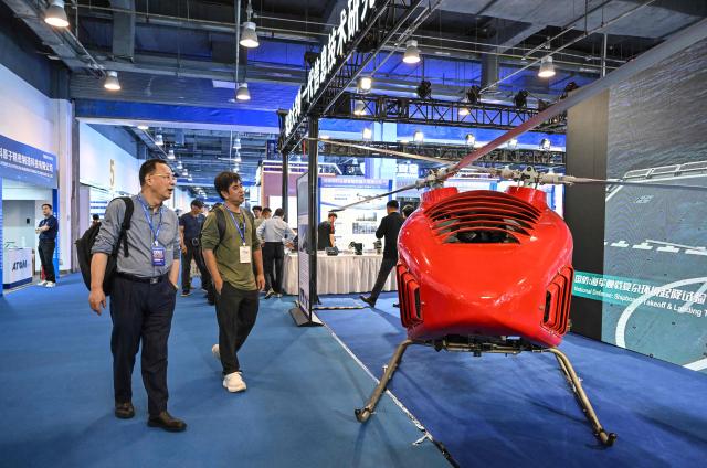 People examine a JZ-550 unmanned synchropter for emergency response produced by Beijing Tsingaero Armament Technology during the 14th China International Defence Electronics Exhibition (CIDEX) in Beijing on September 15, 2026. (Photo by ADEK BERRY / AFP)