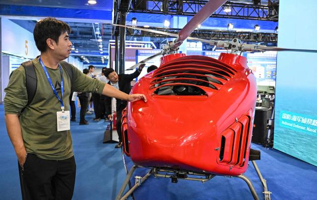 A man examines a JZ-550 unmanned synchropter for emergency response produced by Beijing Tsingaero Armament Technology during the 14th China International Defence Electronics Exhibition (CIDEX) in Beijing on September 15, 2026. (Photo by ADEK BERRY / AFP)