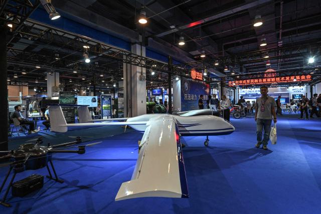 A man walks past unmanned aerial vehicles during the 14th China International Defence Electronics Exhibition (CIDEX) in Beijing on September 15, 2026. (Photo by ADEK BERRY / AFP)