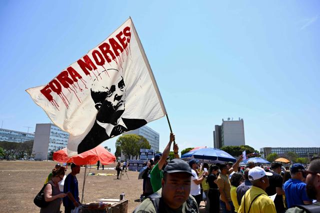 Protesters hold a banner reading "Moraes Out" outside the National Congress in Brasilia on September 15, 2026, during a hearing at Brazil's Supreme Federal Court (STF) on the investigation into alleged links between Supreme Court Justice Alexandre de Moraes and banker Daniel Vorcaro. Brazil's Supreme Court on September 15 began examining one of its top justice's ties to a jailed banker, in an unprecedented crisis that has eclipsed the country's presidential election campaign. (Photo by Evaristo Sa / AFP)