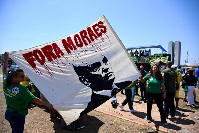 Protesters hold a banner reading "Moraes Out" outside the National Congress in Brasilia on September 15, 2026, during a hearing at Brazil's Supreme Federal Court (STF) on the investigation into alleged links between Supreme Court Justice Alexandre de Moraes and banker Daniel Vorcaro. Brazil's Supreme Court on September 15 began examining one of its top justice's ties to a jailed banker, in an unprecedented crisis that has eclipsed the country's presidential election campaign. (Photo by Evaristo Sa / AFP)