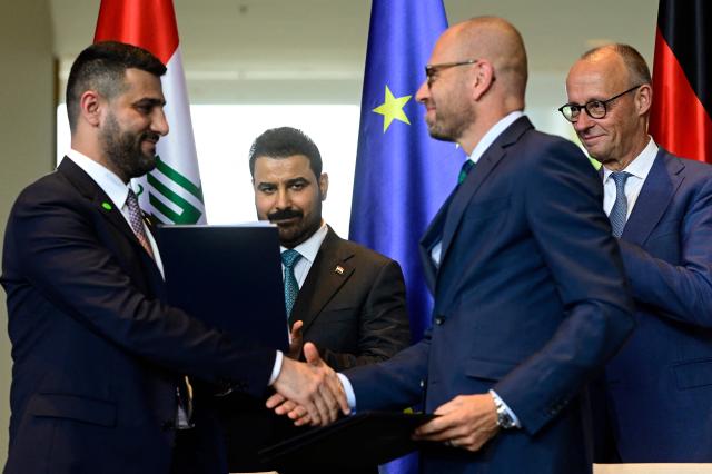 Iraq's Electricity Minister Ali Saad Wahib (L) and Siemens Energy CEO Christian Bruch (2ndR) shake hands after exchanging documents as Iraq's Prime Minister Ali Falih Kadhim al-Zaidi (2ndL) and German Chancellor Friedrich Merz (R) look on at the Chancellery in Berlin, on September 15, 2026. (Photo by John MACDOUGALL / AFP)
