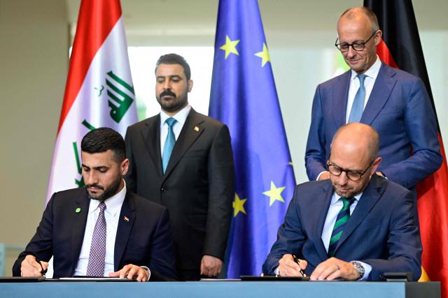 Iraq's Energy Minister Ali Saad Wahib (L) and Siemens Energy CEO Christian Bruch (R) sign documents as Iraq's Prime Minister Ali Falih Kadhim al-Zaidi (2ndL) and German Chancellor Friedrich Merz (R) look on at the Chancellery in Berlin, on September 15, 2026. (Photo by John MACDOUGALL / AFP)