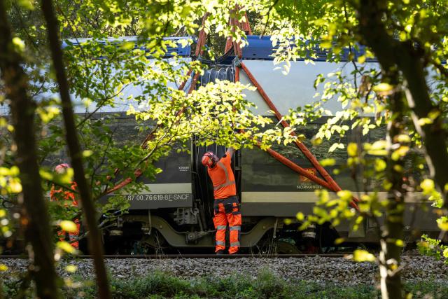 Railway workers operate next to a train during the beginning of the lifting opérations of the derailled train in Cléon, northwestern France, on September 15, 2026. Giant cranes began on September 15, 2026, to lift the first car of the train that derailed near Rouen at the end of last week, AFP journalists observed at the scene of the accident, in Cléon (Seine-Maritime). (Photo by Guillaume SALIGOT / AFP)